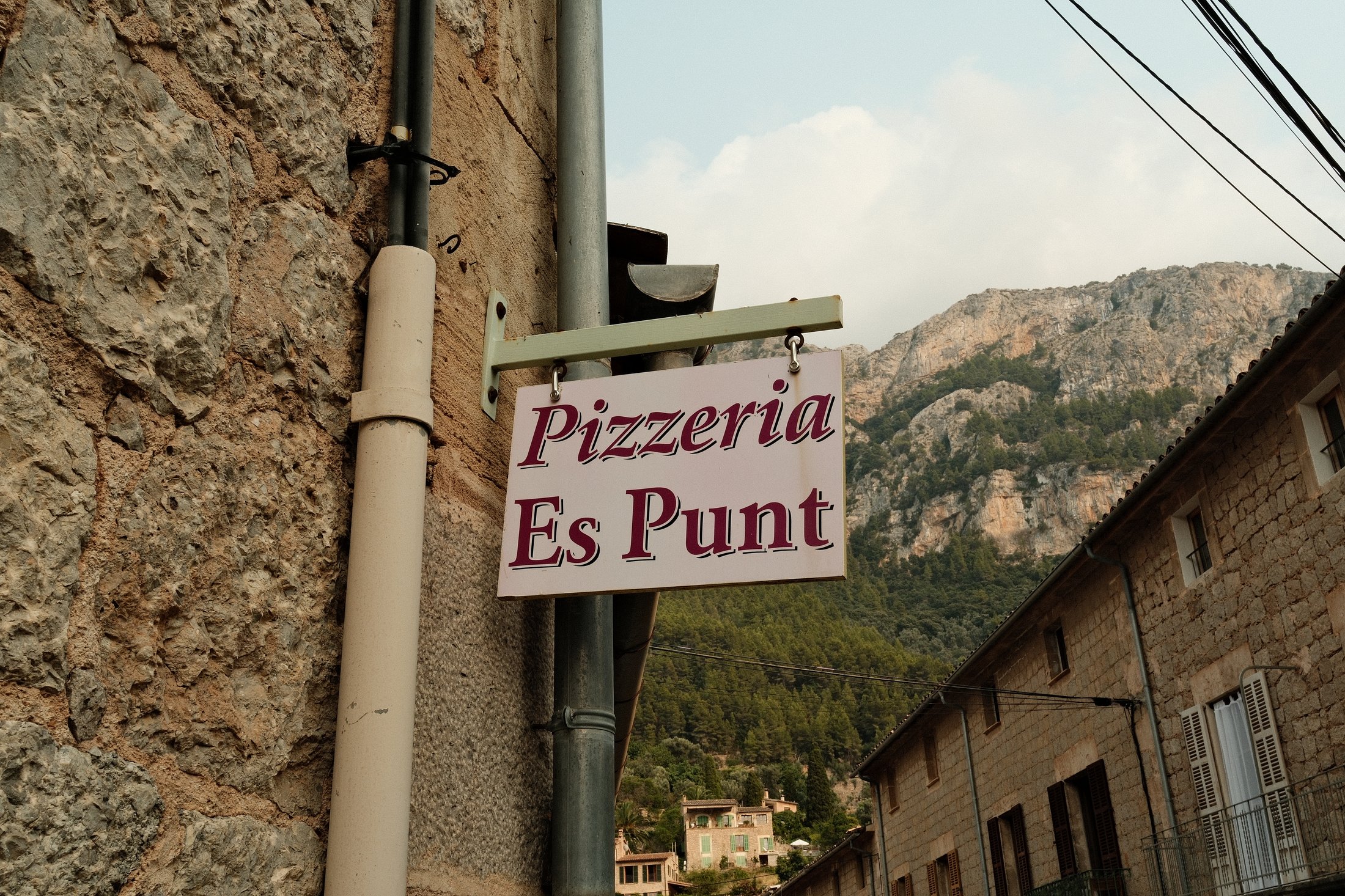 Pizzeria sign against the mountains
